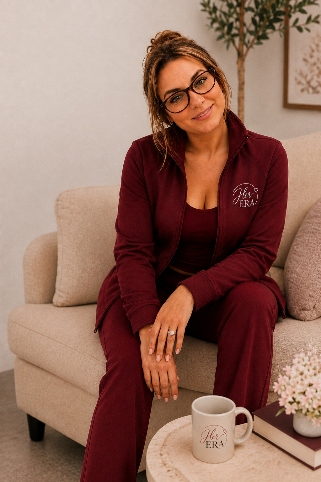 Amy, founder of Her Era, seated in a burgundy zip track set
